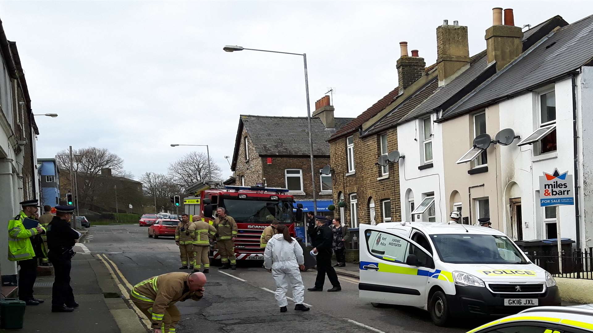 The house fire scene with a police forensics investigator present