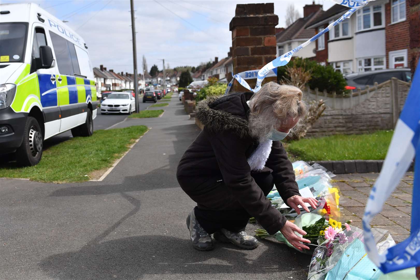 A woman puts flowers down outside the house on Boundary Avenue in Rowley Regis (Jacob King/PA)