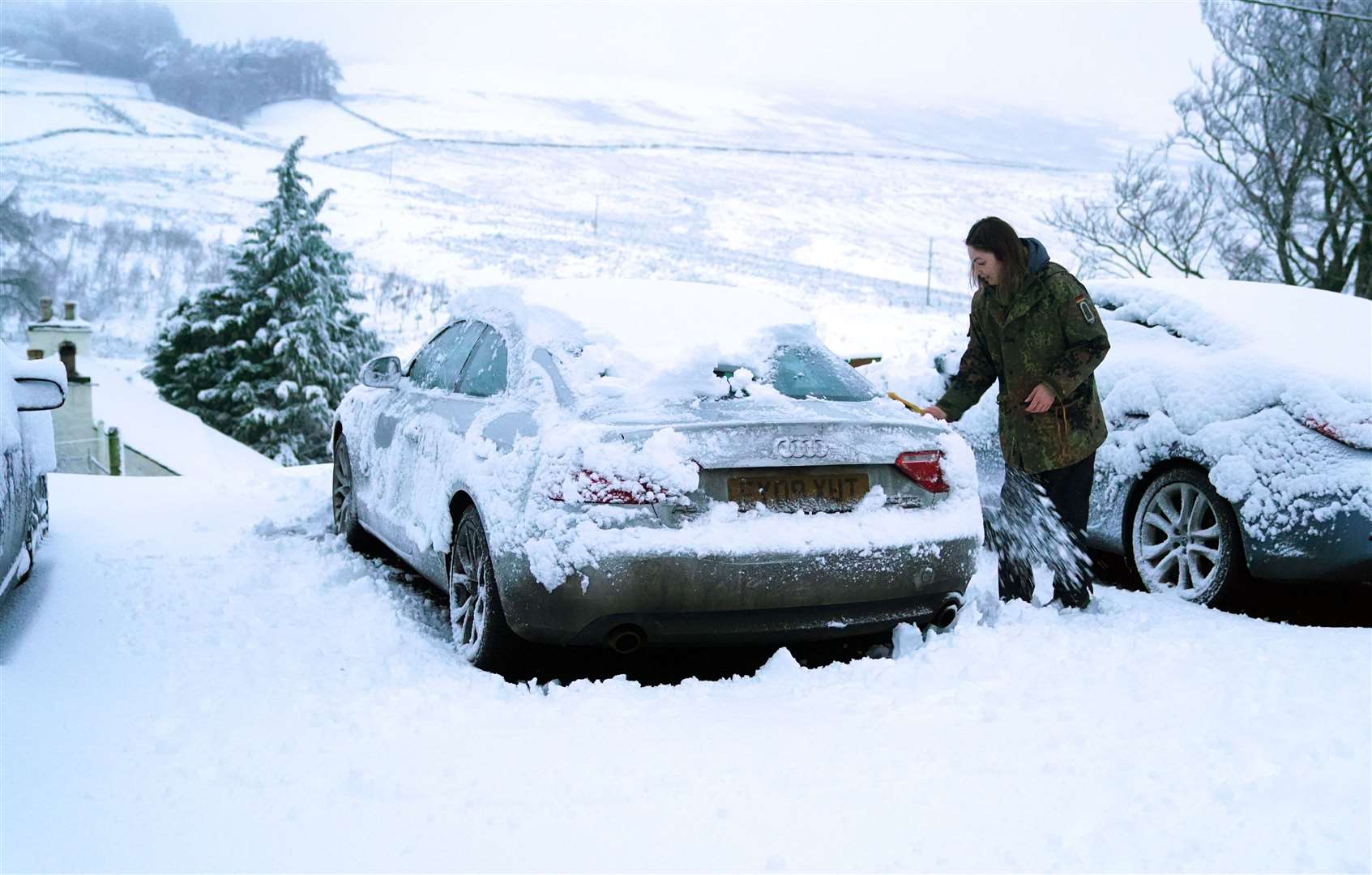 A Carrshield motorist clears snow from her car (Owen Humphreys/PA)