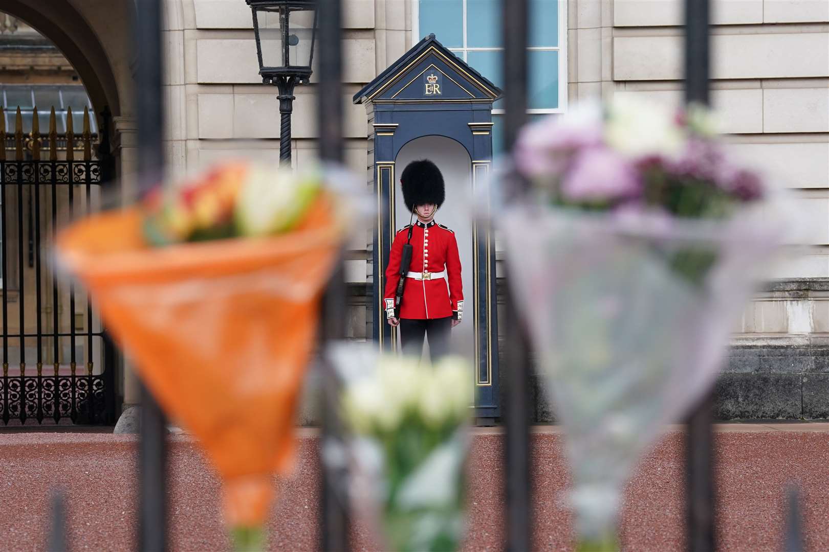 Bouquets of flowers are left on the gate at Buckingham Palace (Kirsty O’Connor/PA)