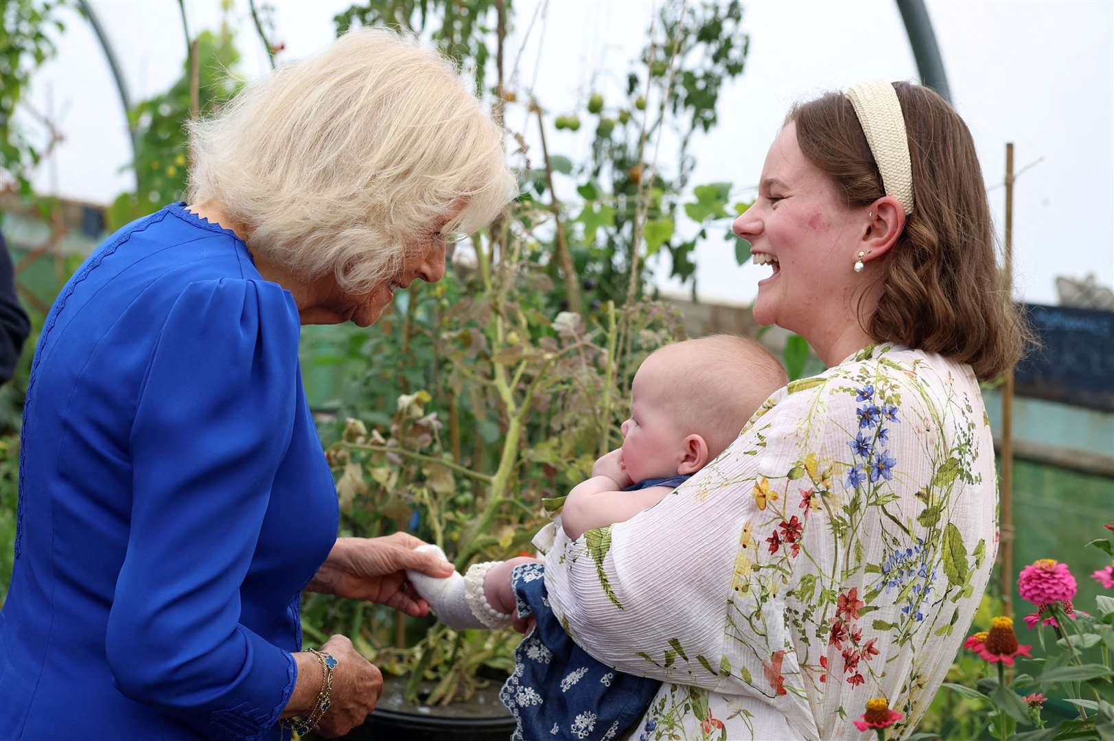 Camilla meets three–month–old Rose Stubbings and her mother Harriet in the allotment (Phil Noble/PA)