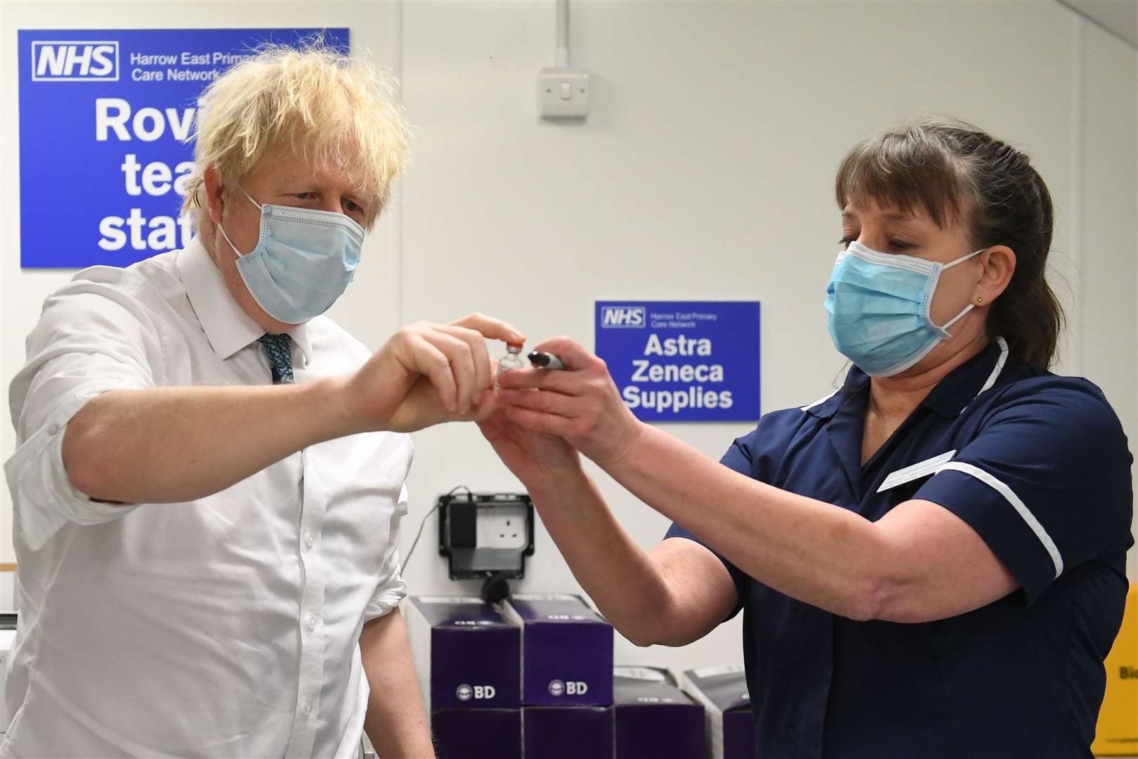 Prime Minister Boris Johnson is shown a vial of the Oxford/AstraZeneca coronavirus vaccine during a visit to Barnet FC’s ground at The Hive, north London, which is being used as a coronavirus vaccination centre (Stefan Rousseau/PA)