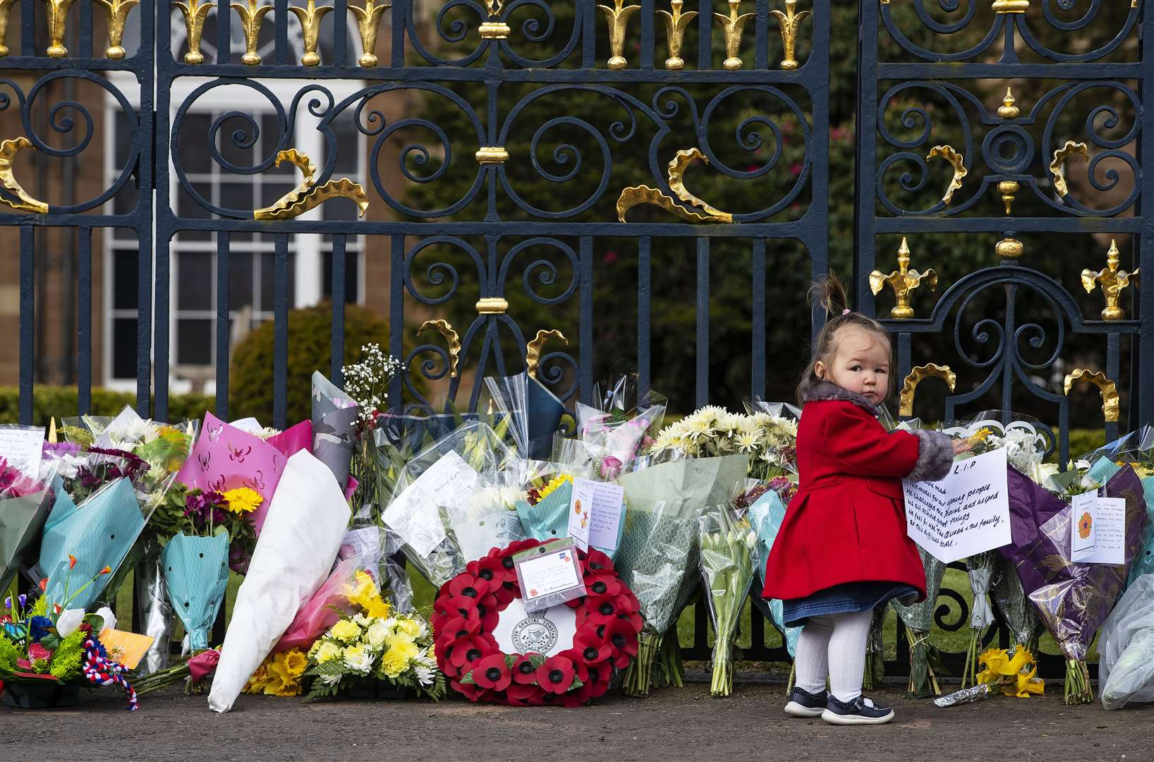 Maise Cairns, aged 18 months, at the gates of Hillsborough Castle during a 41-round gun salute following the announcement of the death of the Duke of Edinburgh (Brian Lawless/PA)