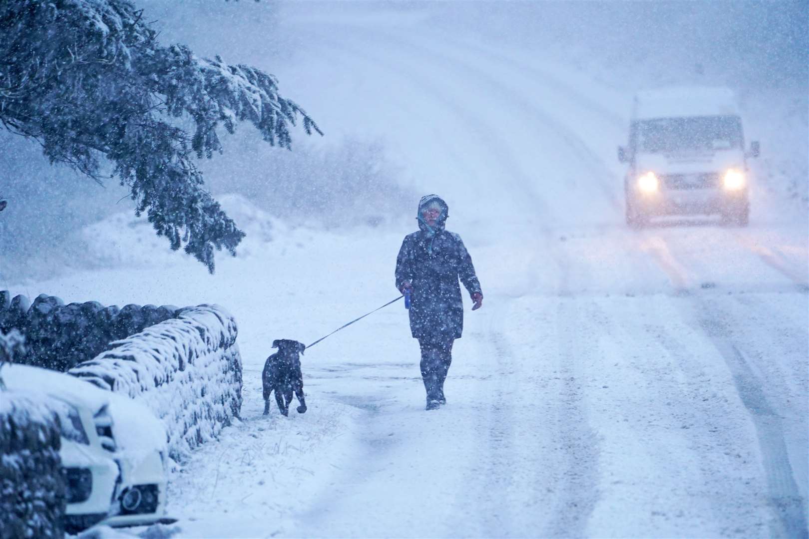 A dog walker walking along a snow covered road in Slaley, Northumberland (Owen Humphreys/PA)