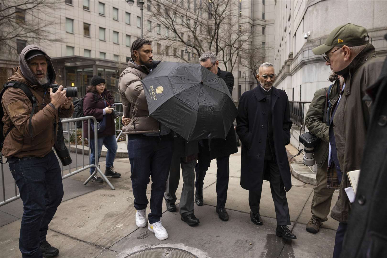 Joe Lewis leaves the court behind an umbrella (Yuki Iwamura/AP)