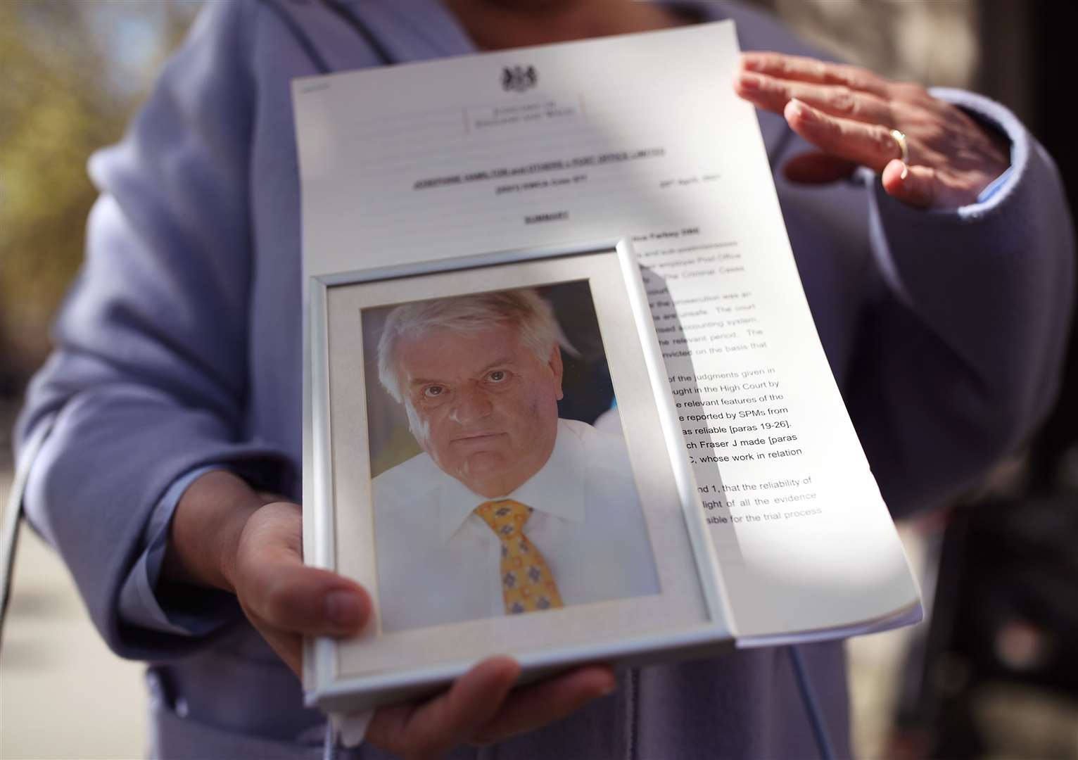 Karen Wilson, widow of postmaster Julian Wilson who died in 2016, holds his picture outside an earlier hearing (PA)