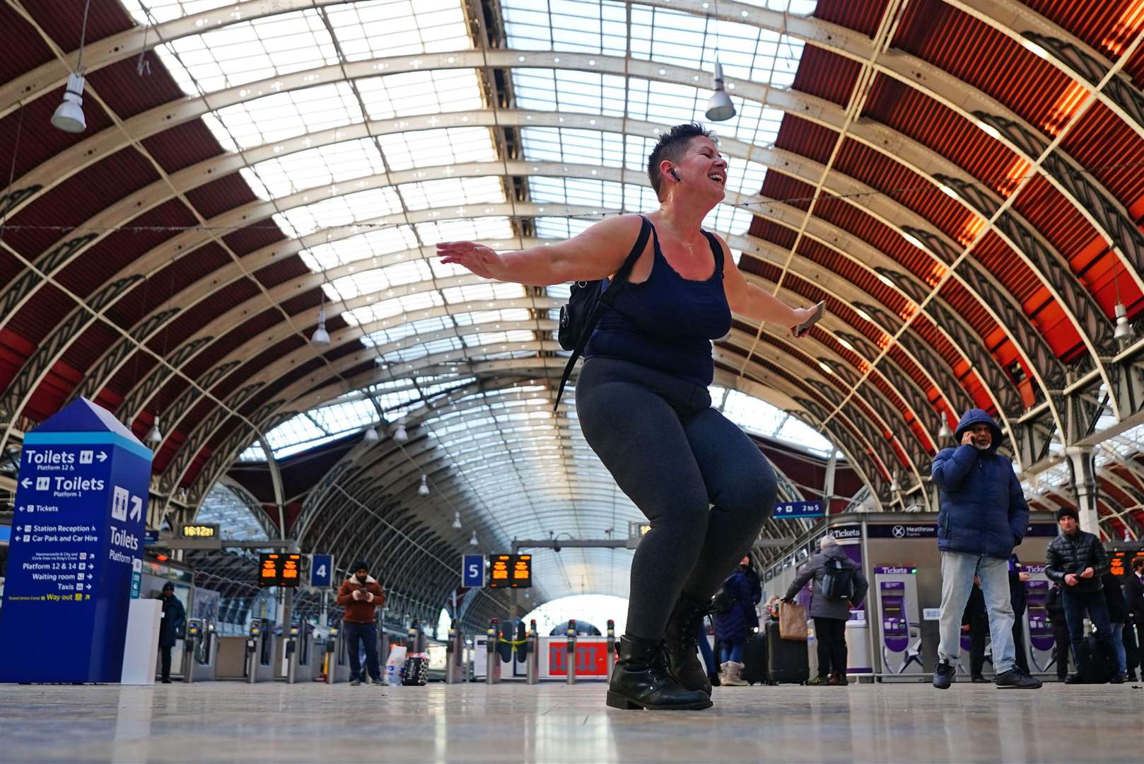 A passenger waiting for a train, who said she had nothing else to do, dancing in Paddington station in London, where trains were cancelled due to Storm Eunice (Victoria Jones/PA)