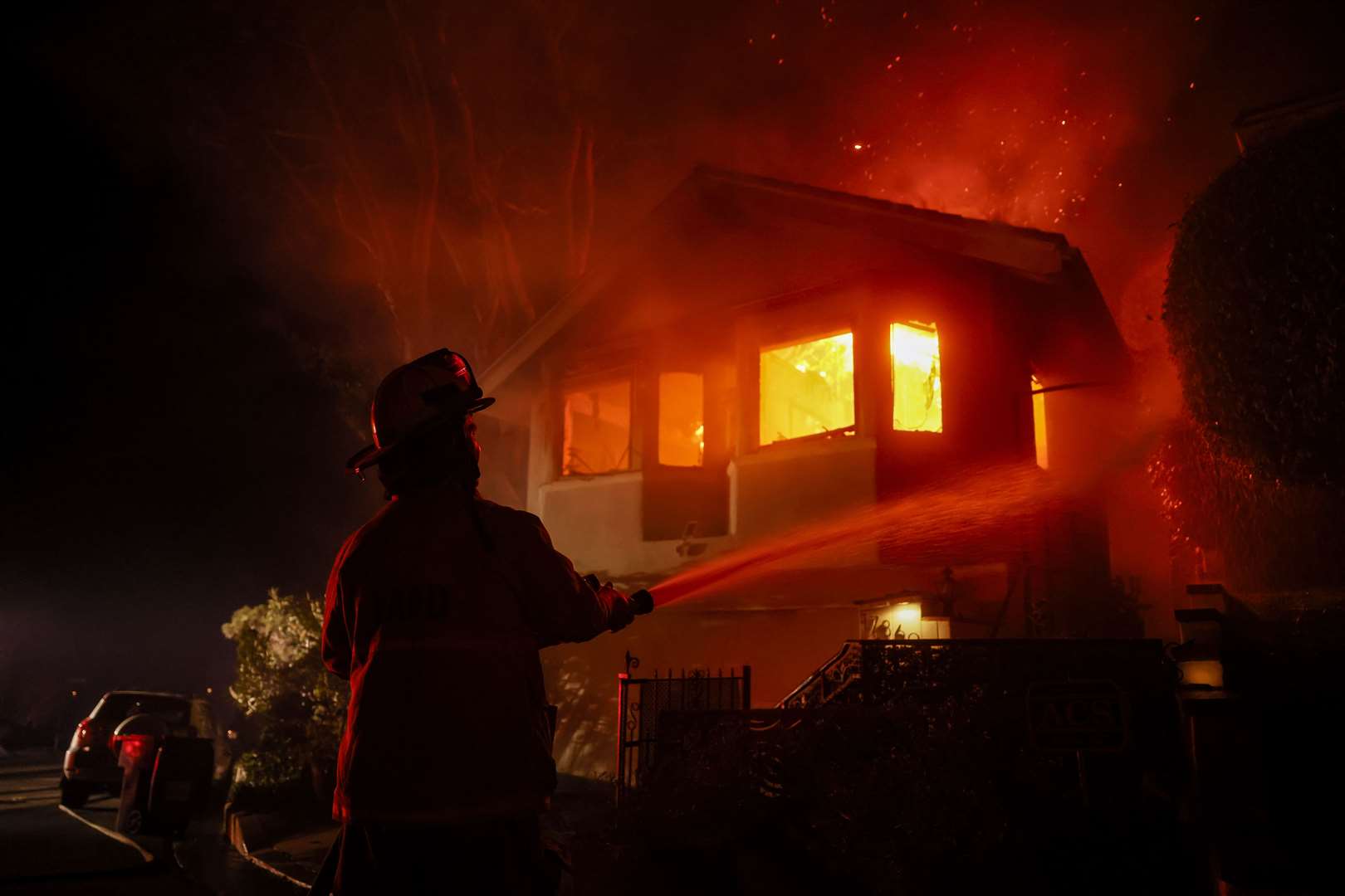 A firefighter works as the Palisades fire burns a house (Etienne Laurent/AP/PA)