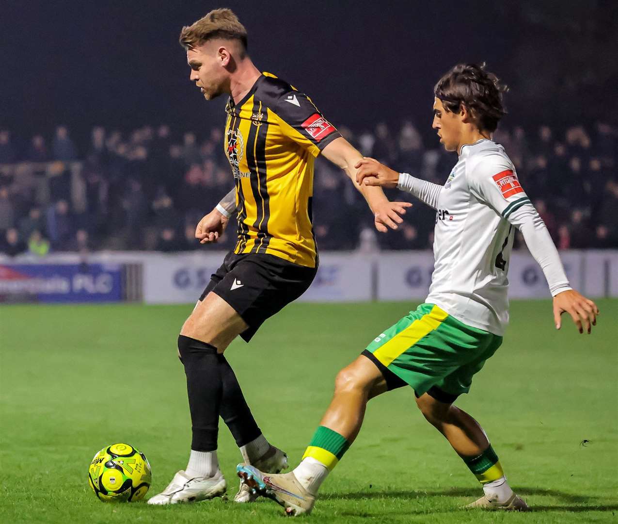 Folkestone midfielder Jack Jebb does battle with Dover’s George Wilkinson. Picture: Helen Cooper