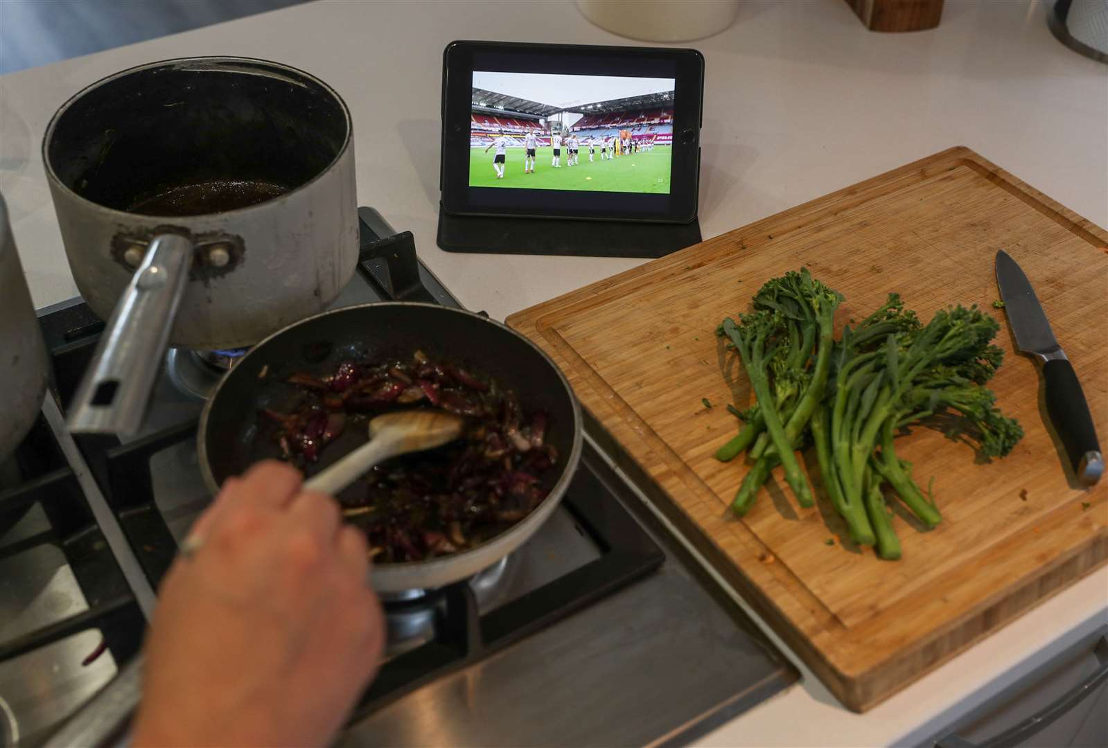 A fan watches the Aston Villa v Sheffield United Premier League match on an iPad as they cook dinner (Andrew Matthews/PA)