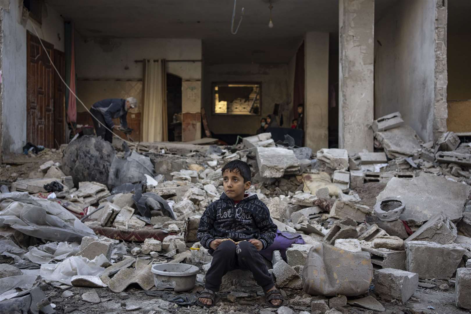 A Palestinian boy sits on the rubble of a building destroyed in an Israeli air strike on the southern Gaza Strip (Fatima Shbair/AP)