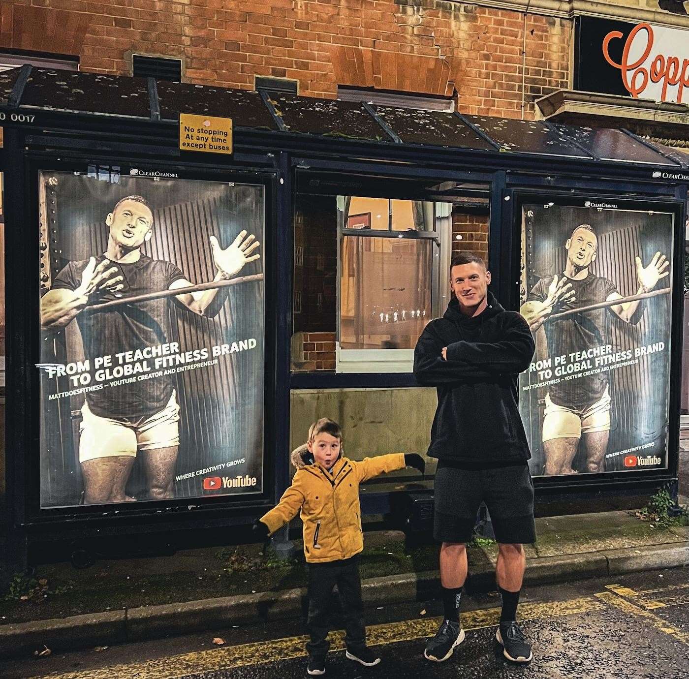 Matt Morsia and son Luca pose next to a bus stop advert about his YouTube success in Hythe. Picture: Instagram / Morsia