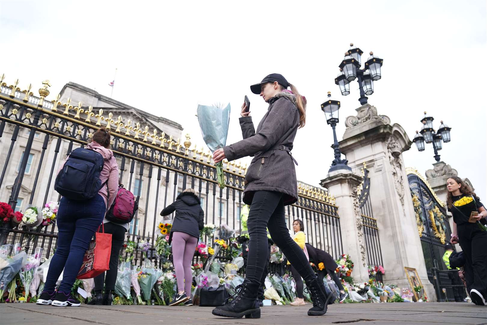 A woman lays flowers at Buckingham Palace (Kirsty O’Connor/PA)