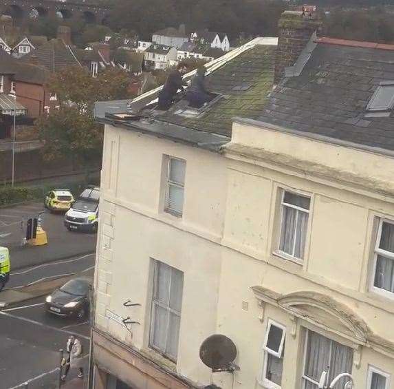 One of the raiders is guided back inside the building in Guildhall Street, Folkestone, through the roof hatch