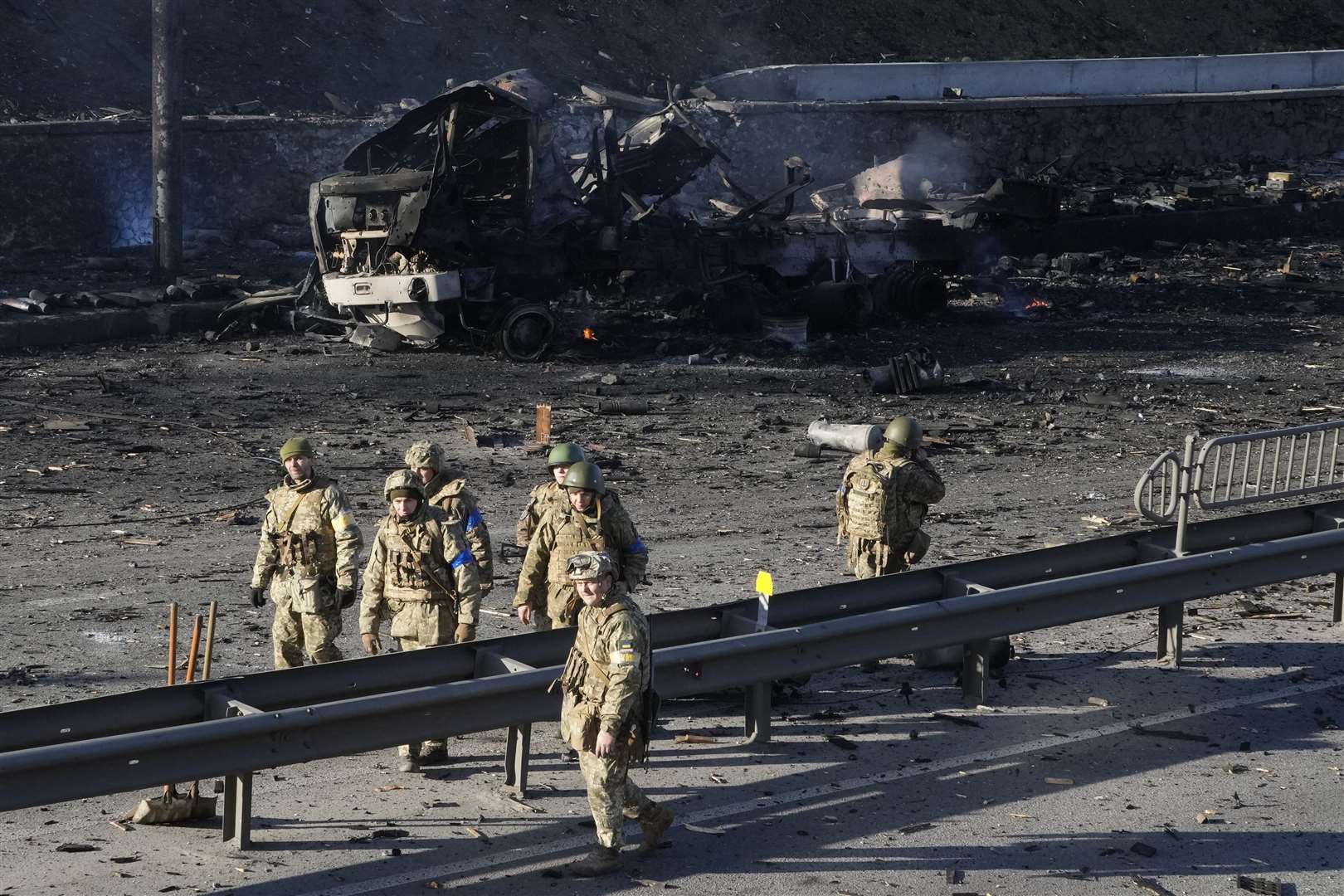 Ukrainian soldiers walk past debris of a burning military truck on a street in Kyiv (Efrem Lukatsky/AP/PA)