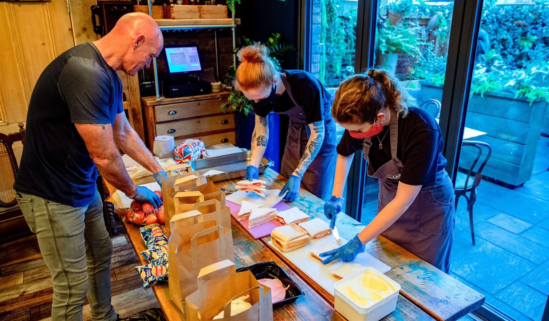 Owner Keith Perryman (left) and staff Helen Manning and Owen Kirkwood prepare sandwiches in The Watering Can, in Greenbank Park, Liverpool