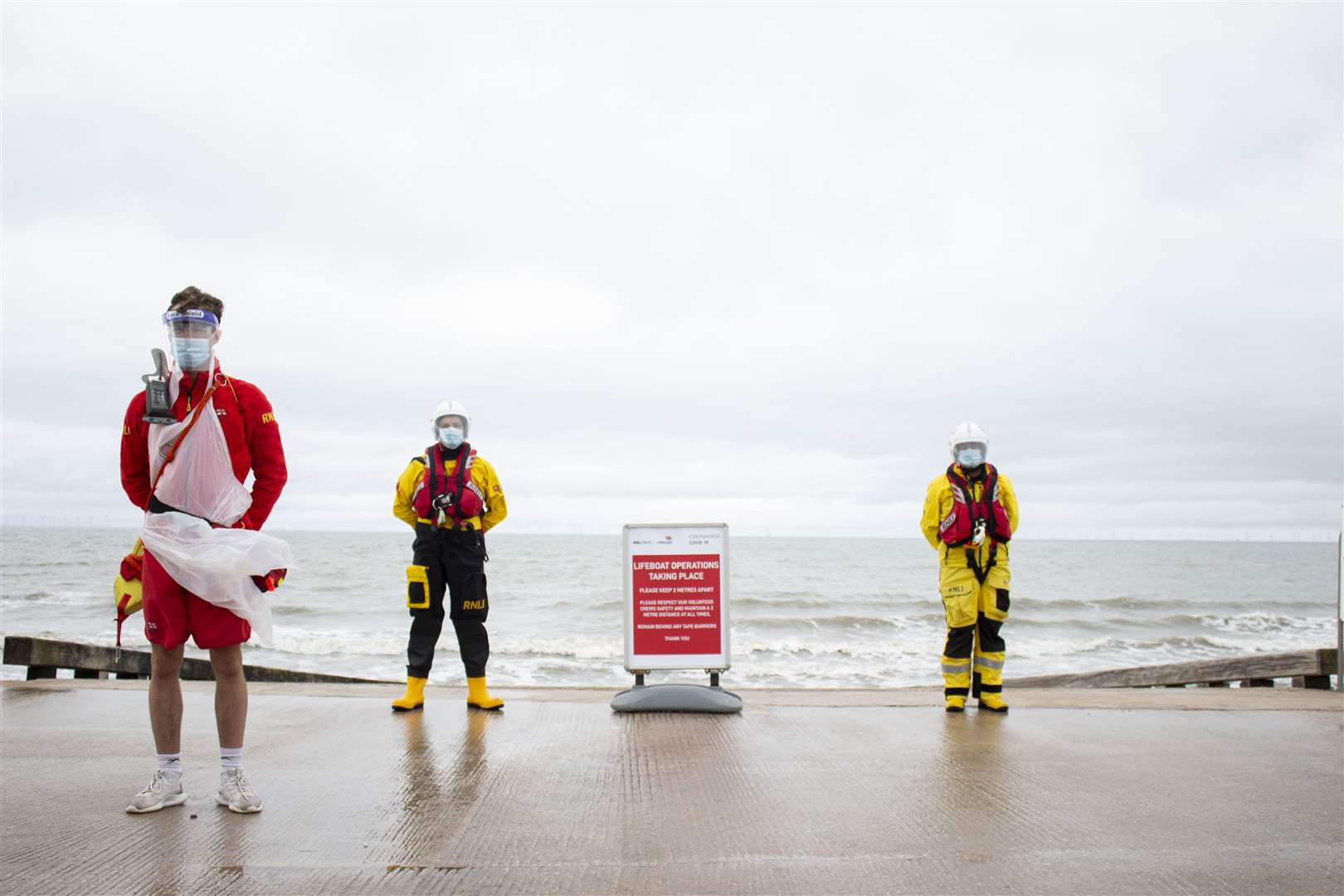 Lifeboat crew members and a lifeguard wear PPE in Rhyl (Callum Robinson/RNLI)