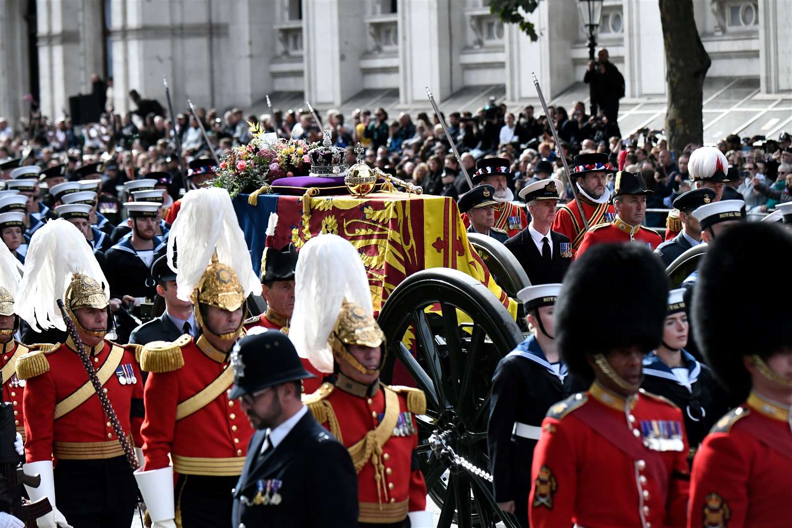 A policeman bows his head as The State Gun Carriage carries the coffin of Queen Elizabeth II, draped in the Royal Standard with the Imperial State Crown and the Sovereign’s orb and sceptre (Stephane De Sakutin/PA)