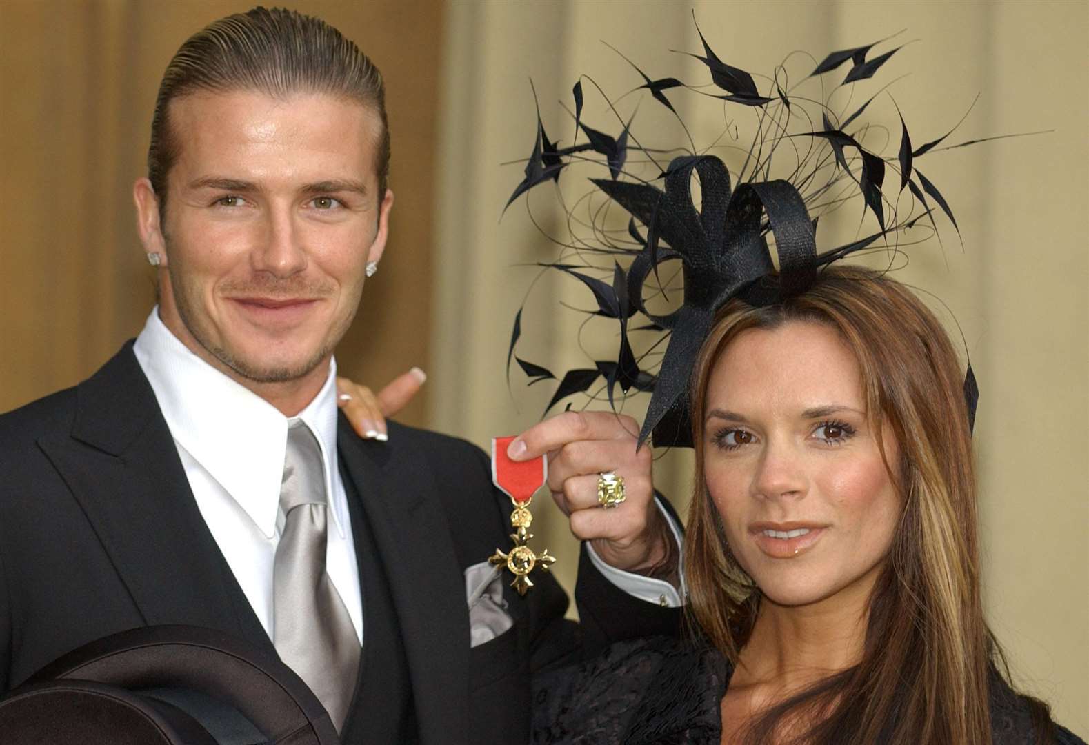 Then-England football captain David Beckham stands with his wife, Victoria, as he shows off the OBE (Fiona Hanson/PA)