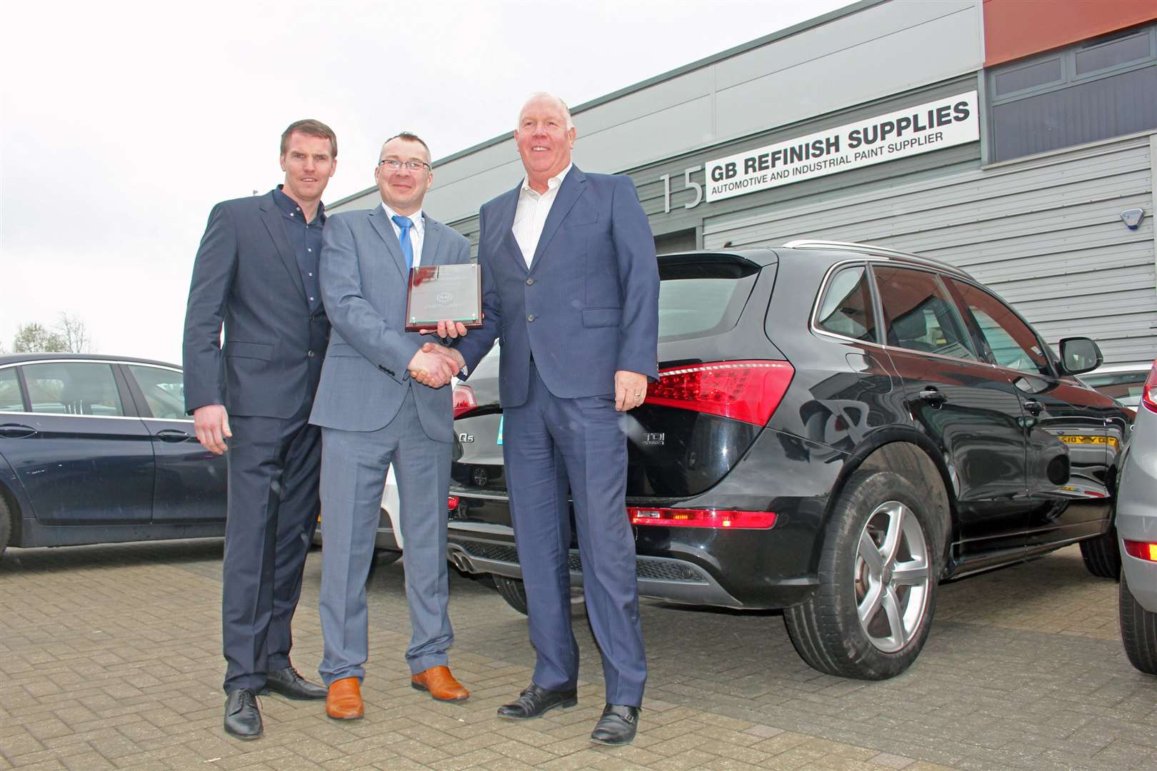 GB Refinish's John Barclay, right, receives an engraved plaque alongside his son John R Barclay, left, from R-M Paint's Darren Barge, celebrating 30 years in business and 20 years with R-M Paint