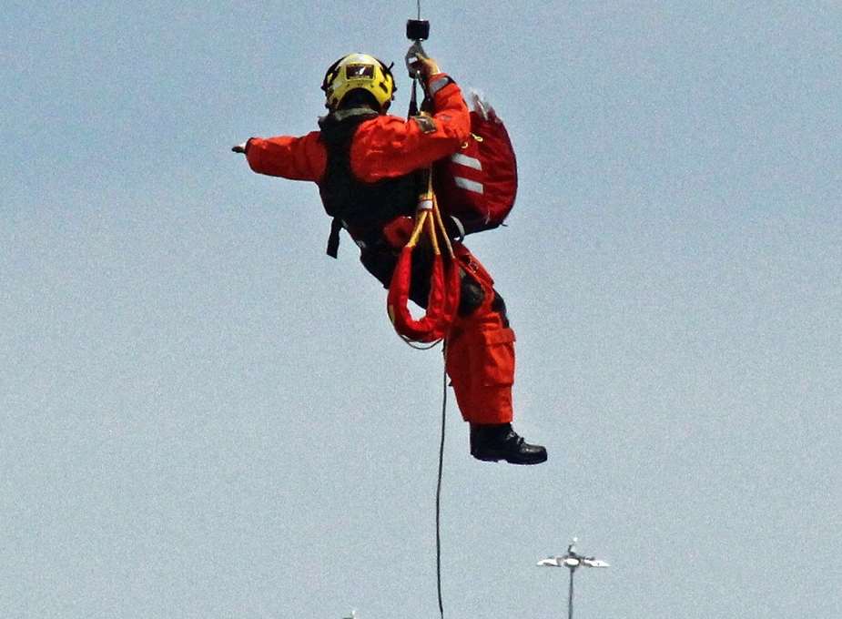 A coastguard crew member suspended under the helicopter. Picture: Nigel Scutt