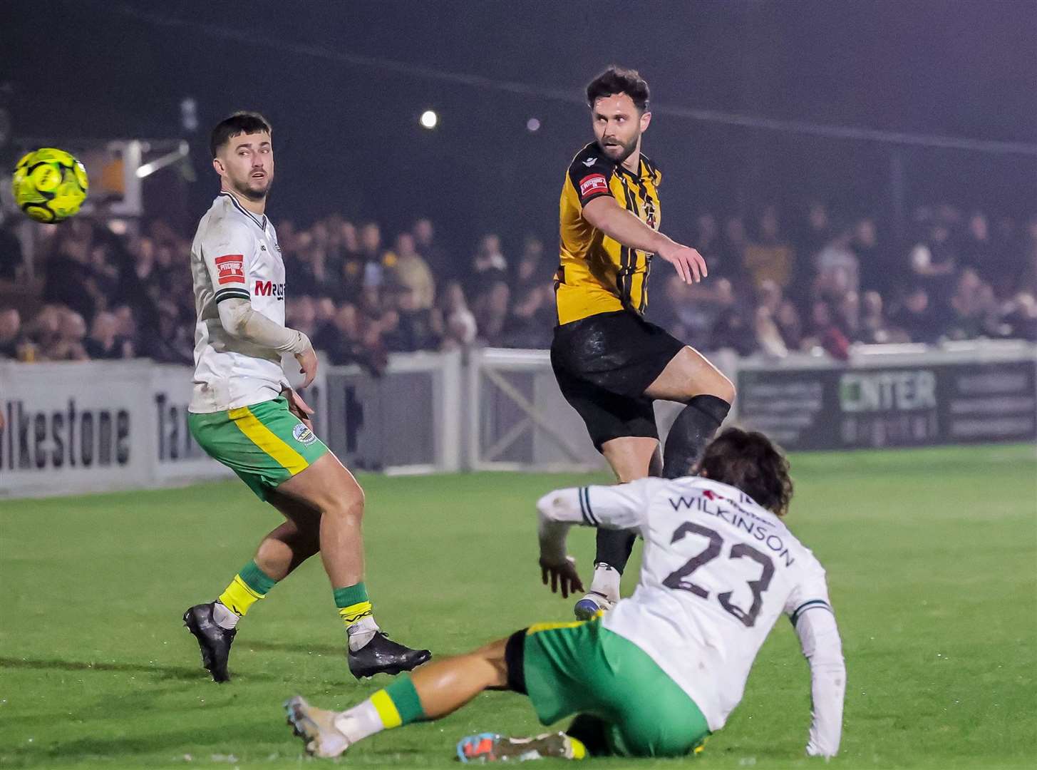 Dean Rance heads towards goal for Folkestone while Dover's Alfie Matthews watches on and George Wilkinson is on the ground. Picture: Helen Cooper