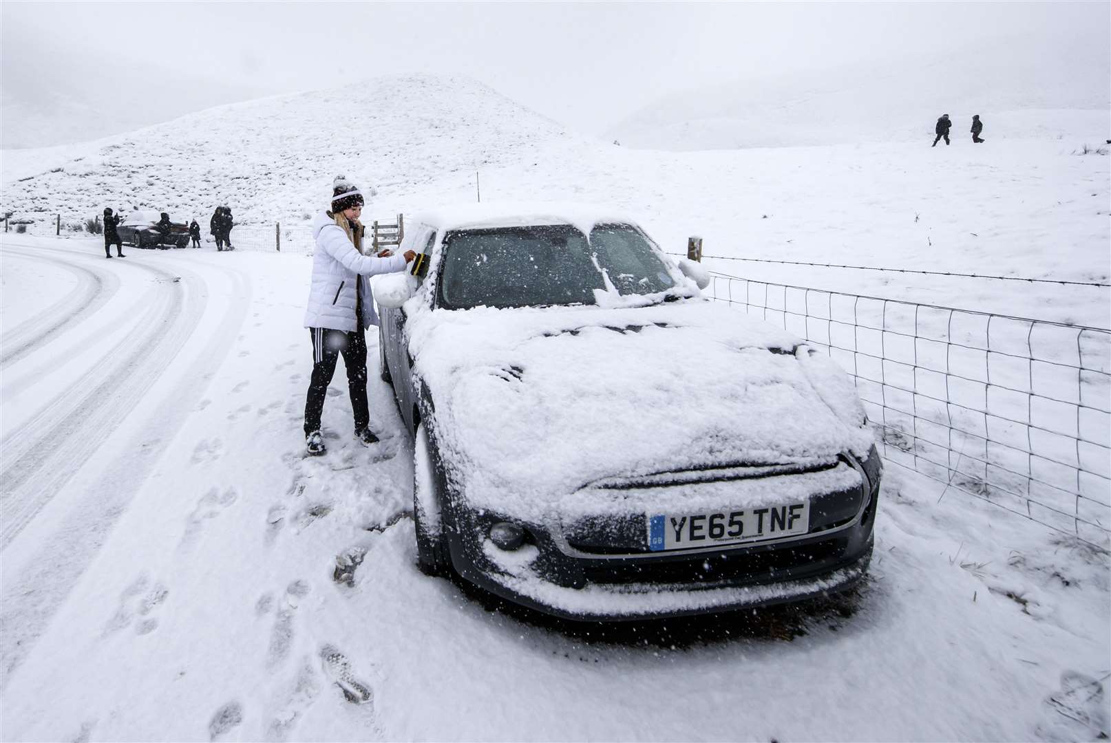 A woman clears snow from her windows near Mam Tor in Derbyshire (Danny Lawson/PA)