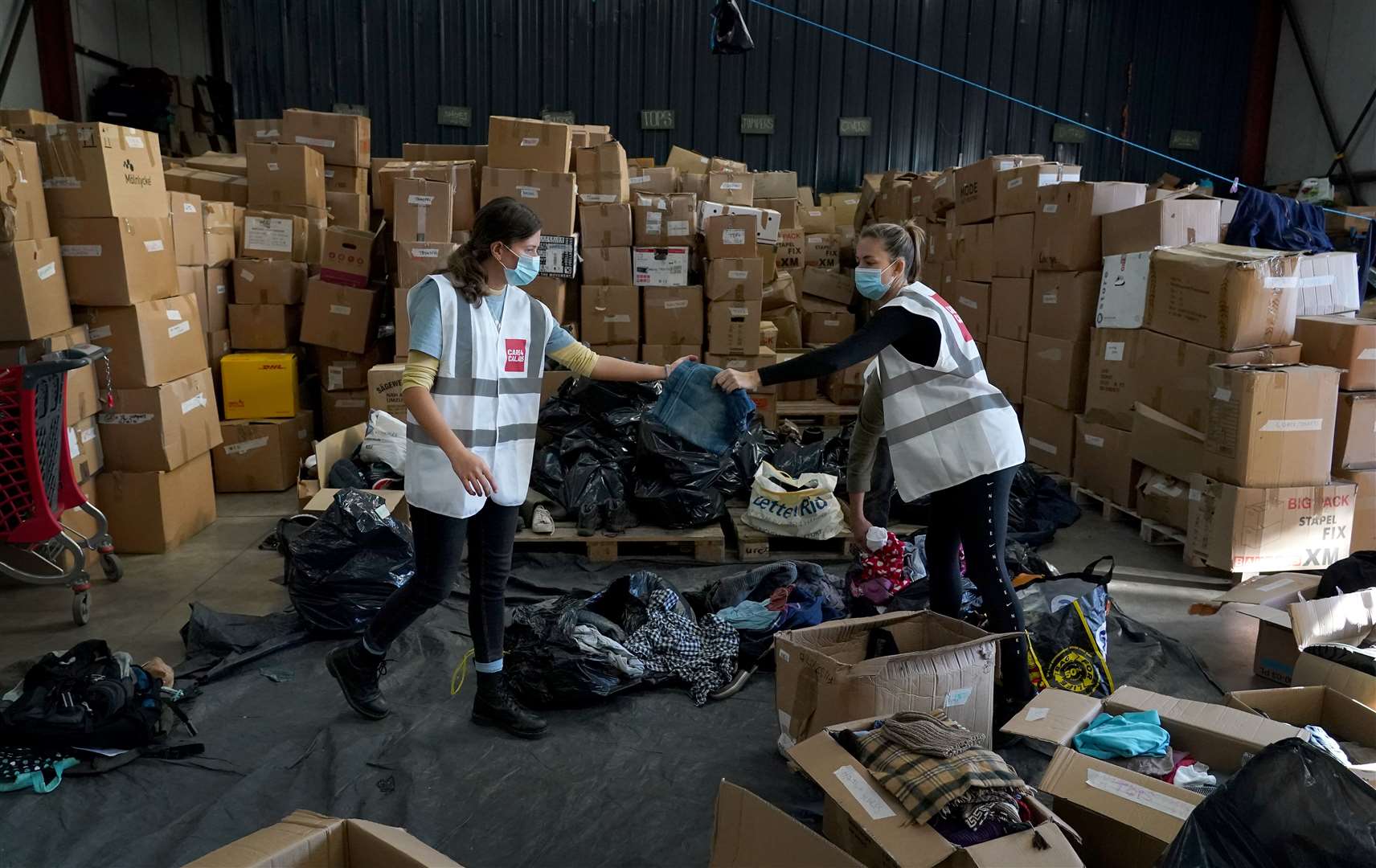 Volunteers go through donated clothes at the Care4Calais warehouse (Gareth Fuller/PA)