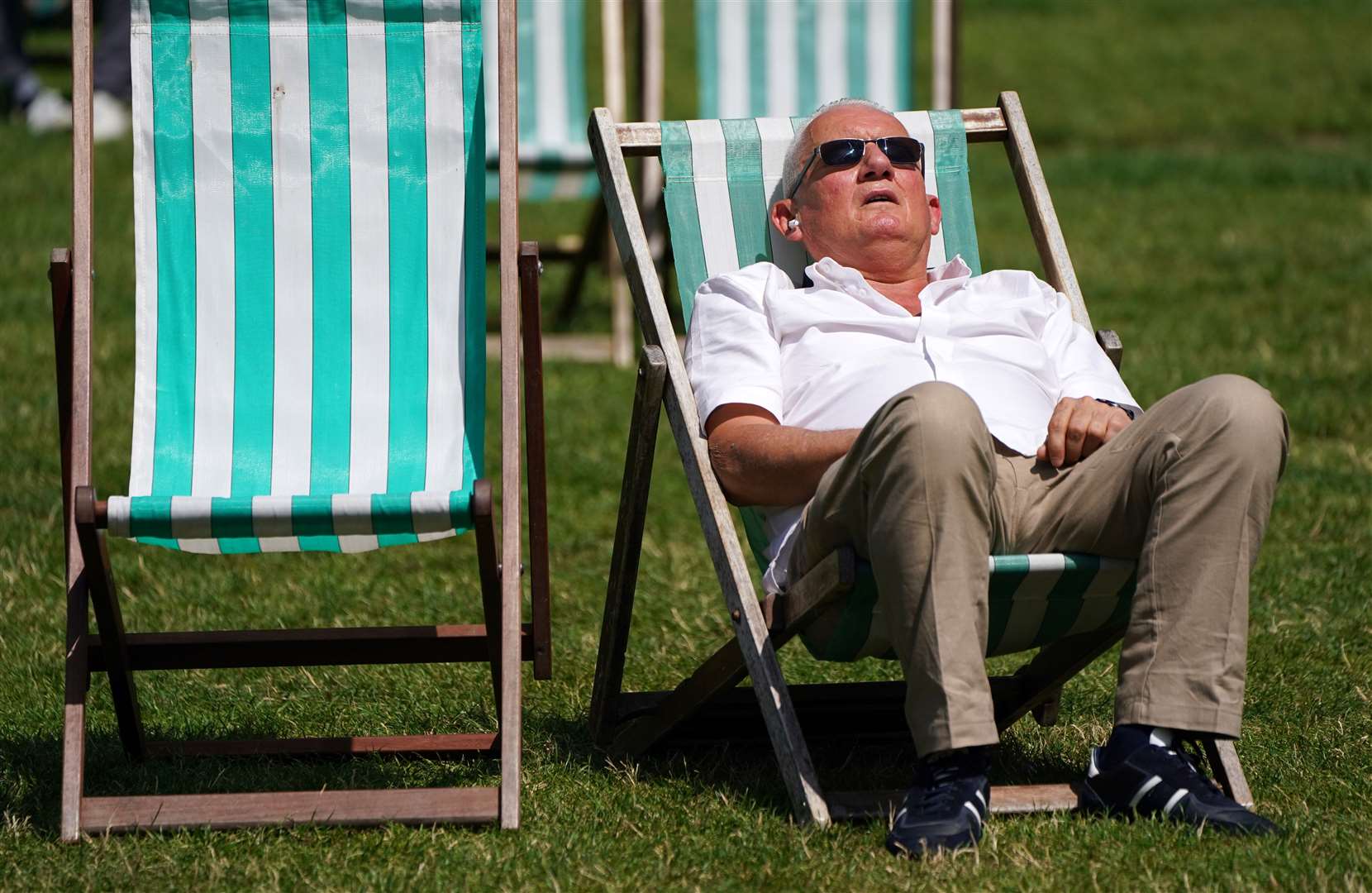 Sunbathers lounge on deck chairs in Green Park, London (Jonathan Brady/PA)