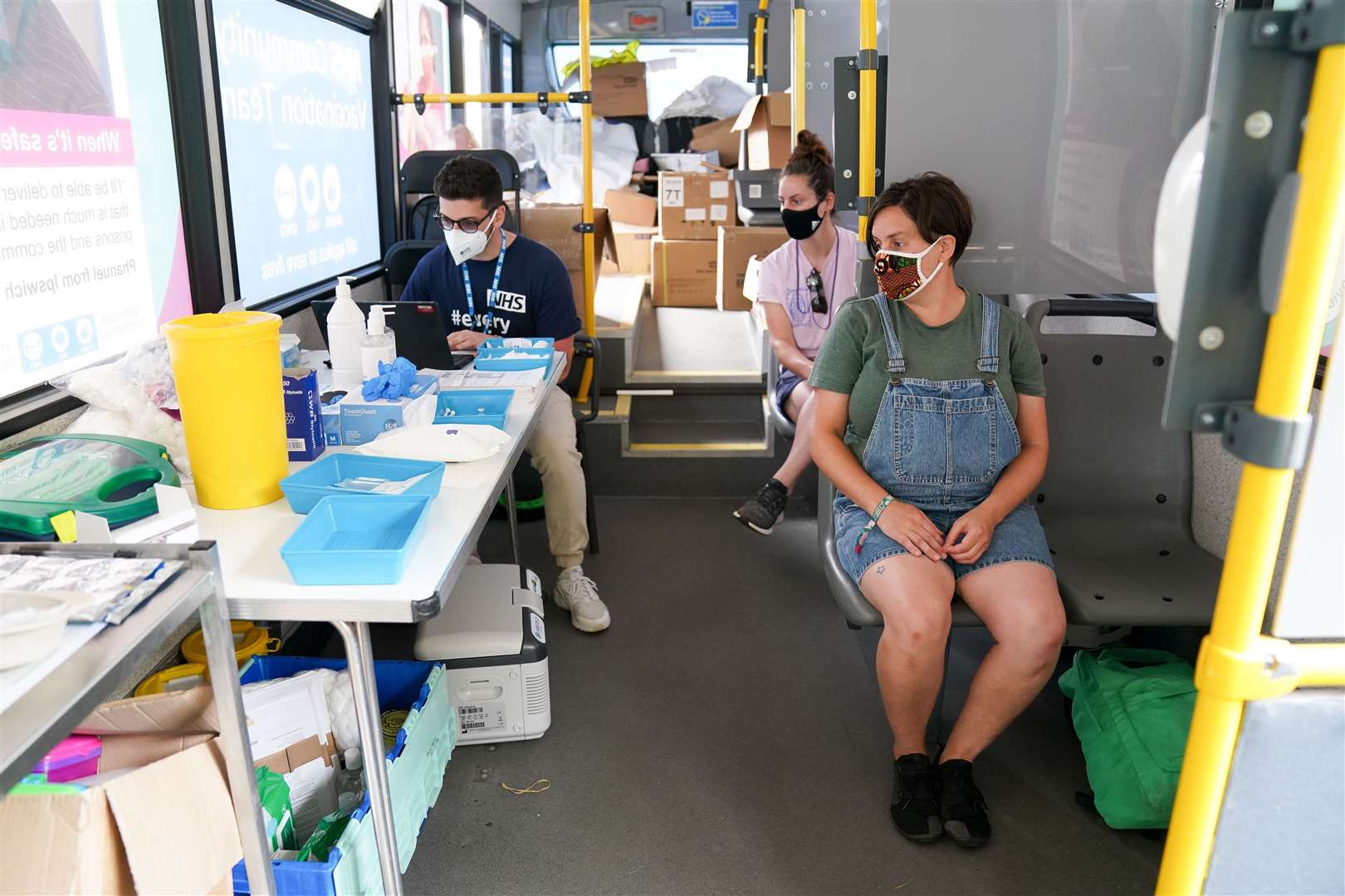 Felicity Perry, right, and her friend Sophie Edmondson wait to be jabbed on the Latitude vaccination bus (Jacob King/PA)