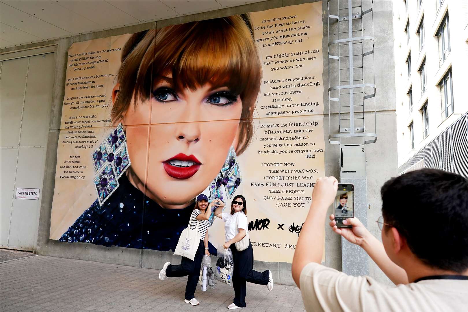 Fans pose for selfies in front of a mural of Taylor Swift outside Wembley Stadium (Aaron Chown/PA)