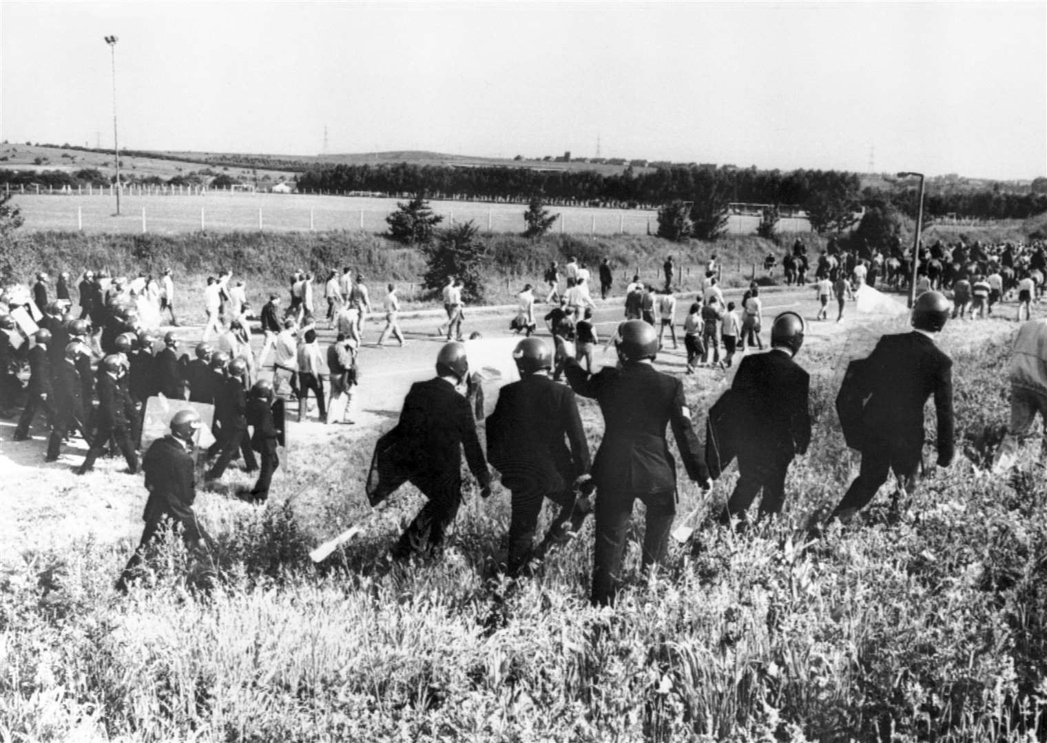 Police in gear escort picketers away from their position near the Orgreave coking plant in South Yorkshire in June 1984 (PA)