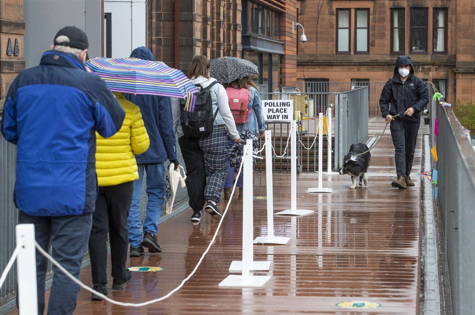 People queue to vote in the Parliamentary election outside the polling station at Notre Dame Primary School in Glasgow (Jane Barlow/PA)