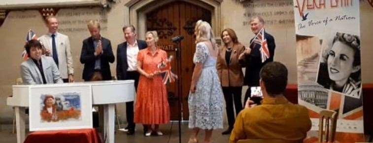 The statue fund committee waves flags to We'll Meet Again sung by Katie Ashby and performed by Dominic Ferris who have produced fundraising record Irreplaceable