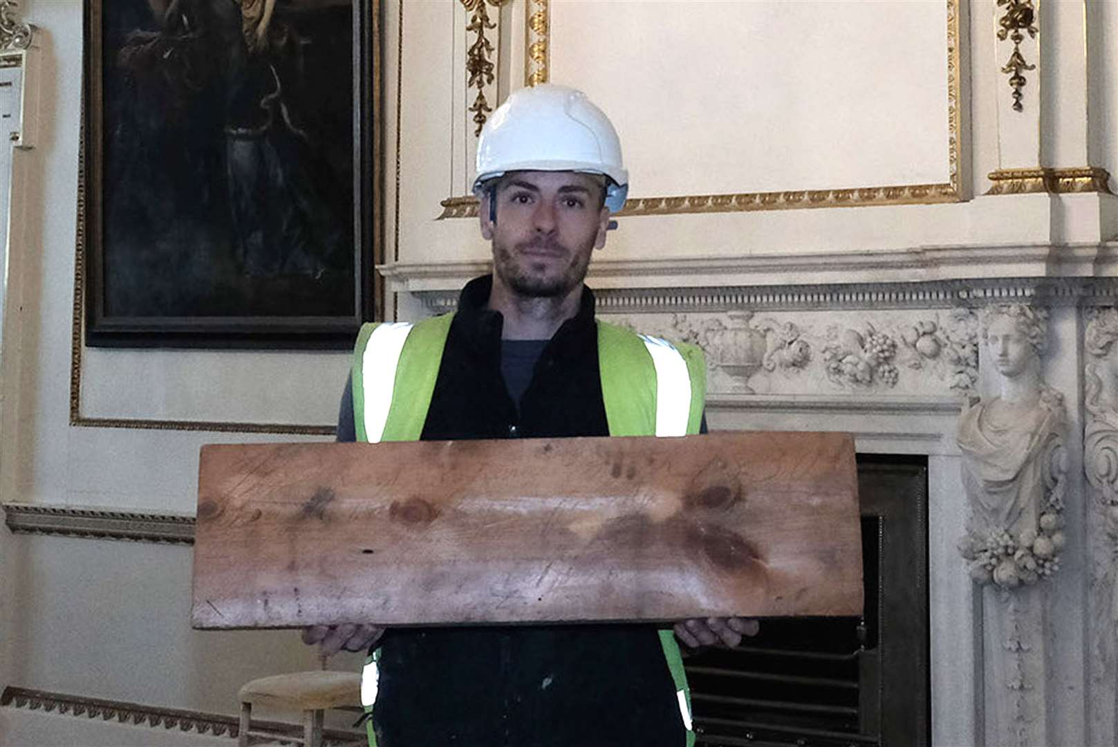 Joe Hutchinson holding an uncovered roof board with an inscription etched into it from 1830 (Steve Mettam/Wentworth Woodhouse Preservation Trust)