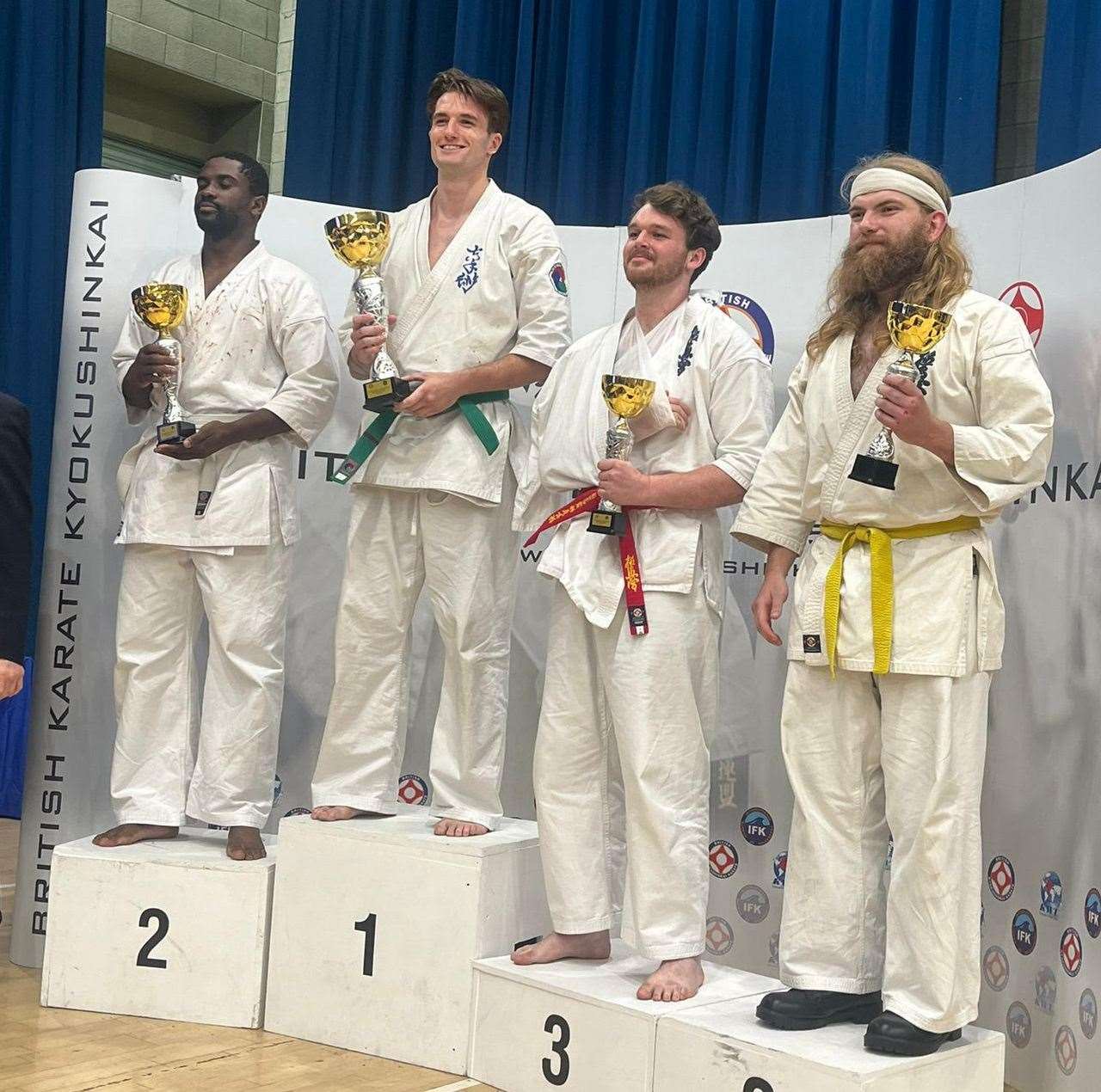 Ashford Karate Jutsu Kai's Joshua Varrier-Smith with his trophy on the top step of the podium after winning the British novice men's heavyweight championship at the BKK British and European Open