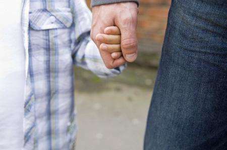 Child holding hands with an adult