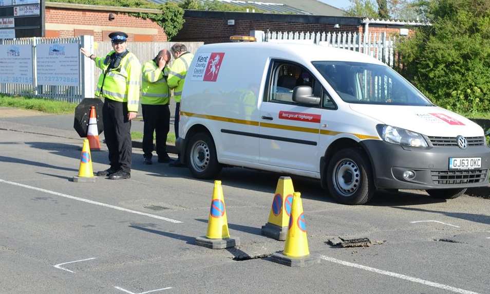 A police officer directs traffic around the hole