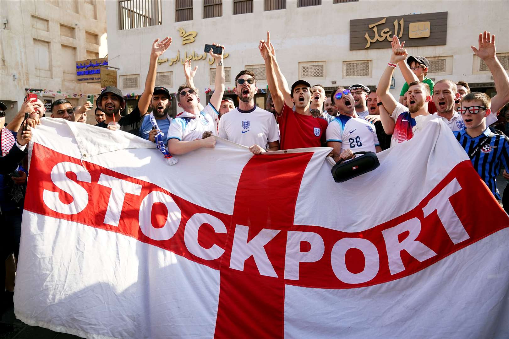 England fans with a Stockport County flag, in the Souk area of Doha (Adam Davy/PA)