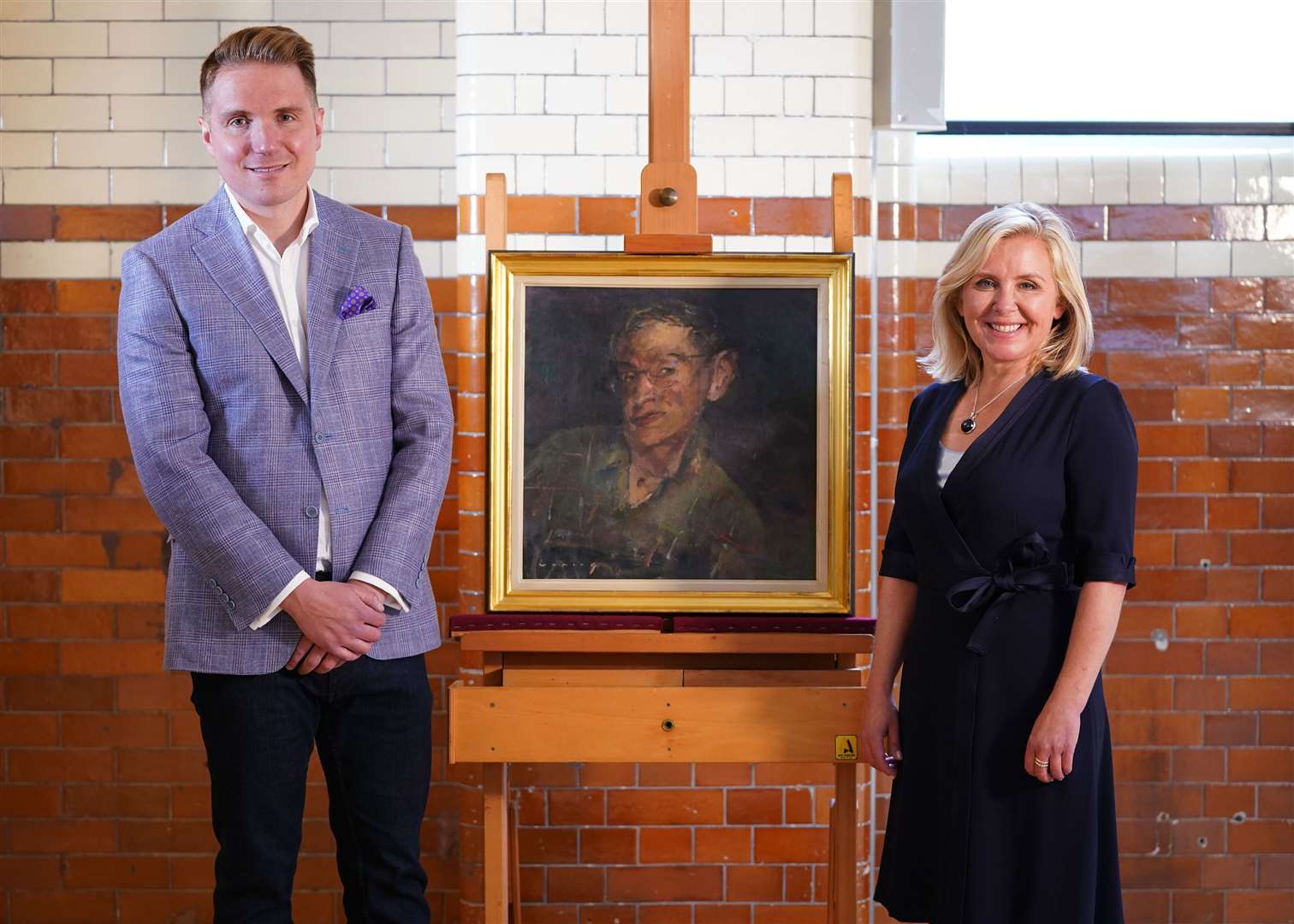 Stephen Hawking’s children Tim and Lucy Hawking pose next to his portrait by Fred Cuming RA, at the Science Museum in London (Yui Mok/PA)