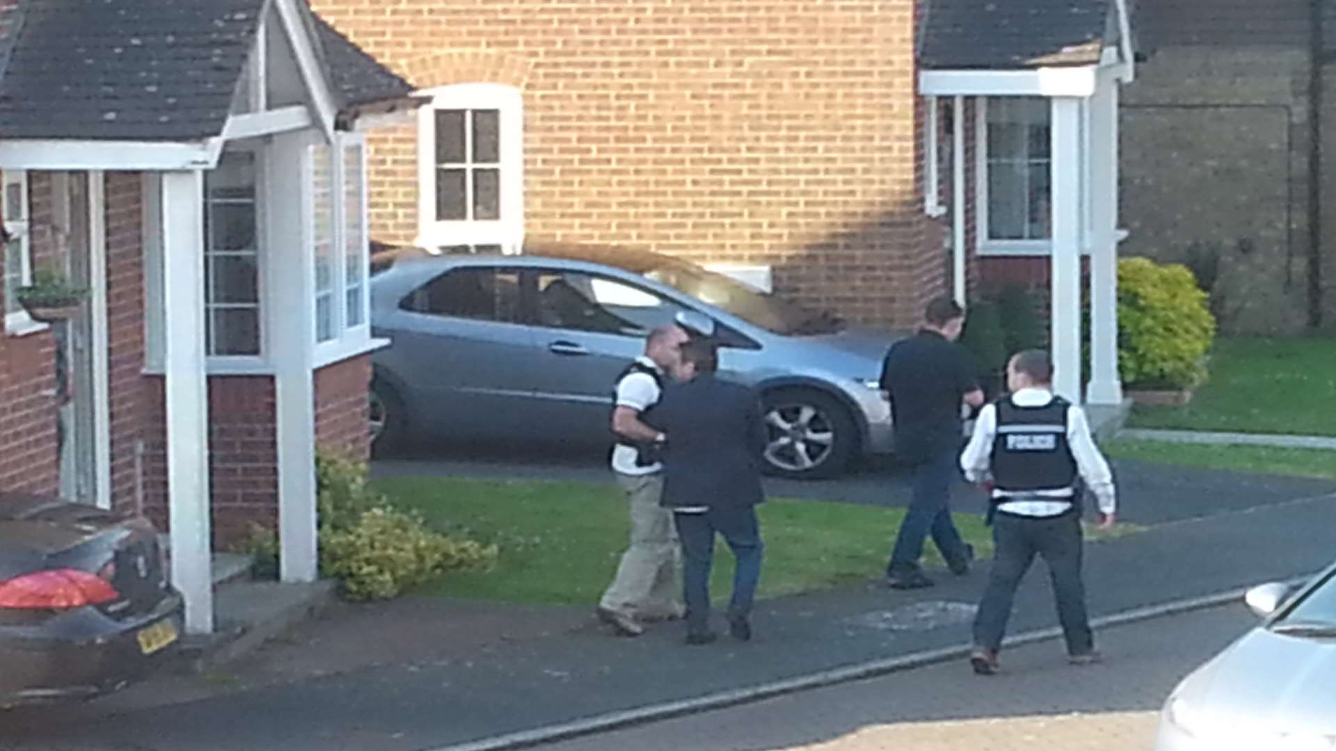 Police escort a man away from the house