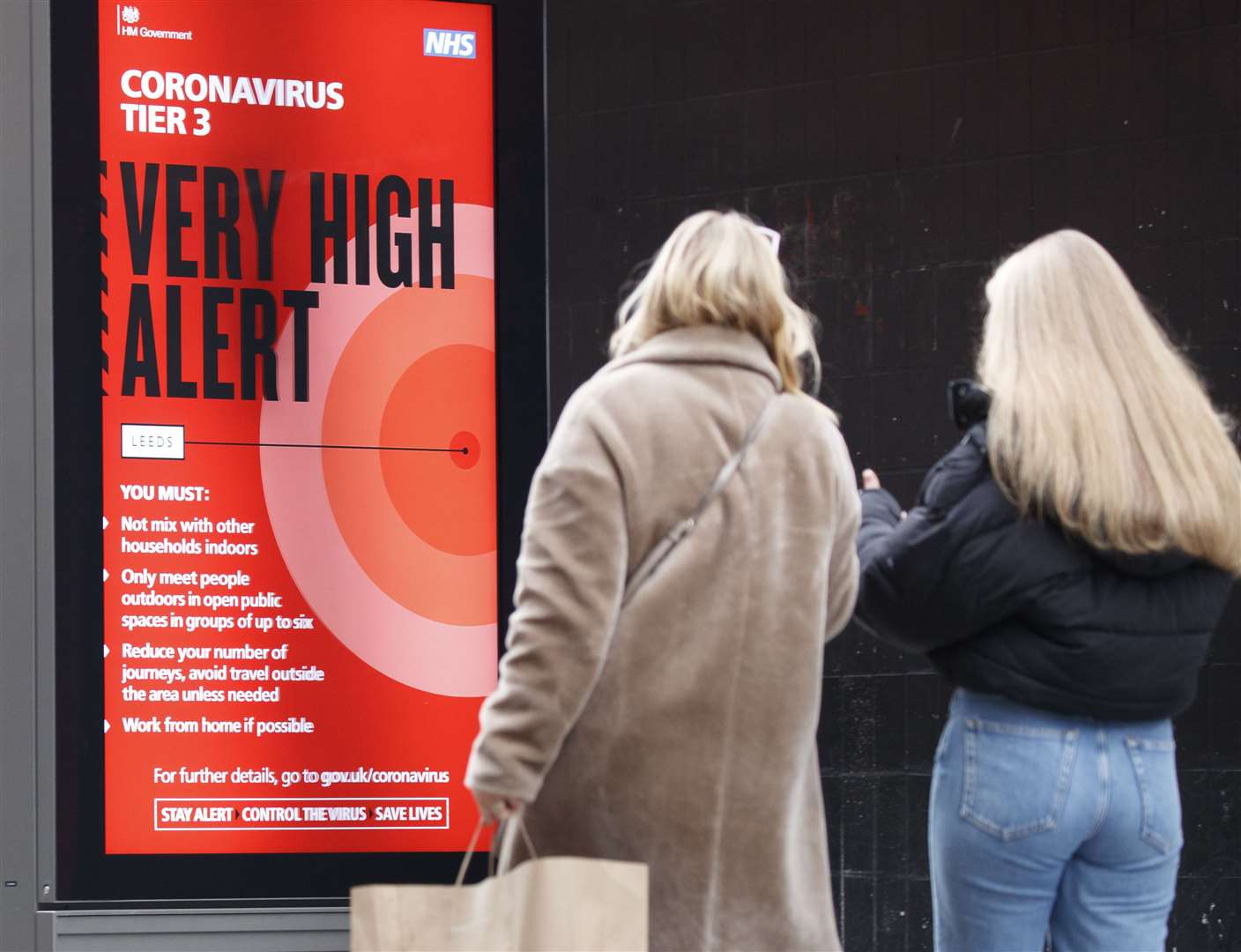 Christmas shoppers walk past a Coronavirus Tier 3 Very High Alert sign (Danny Lawson/PA)