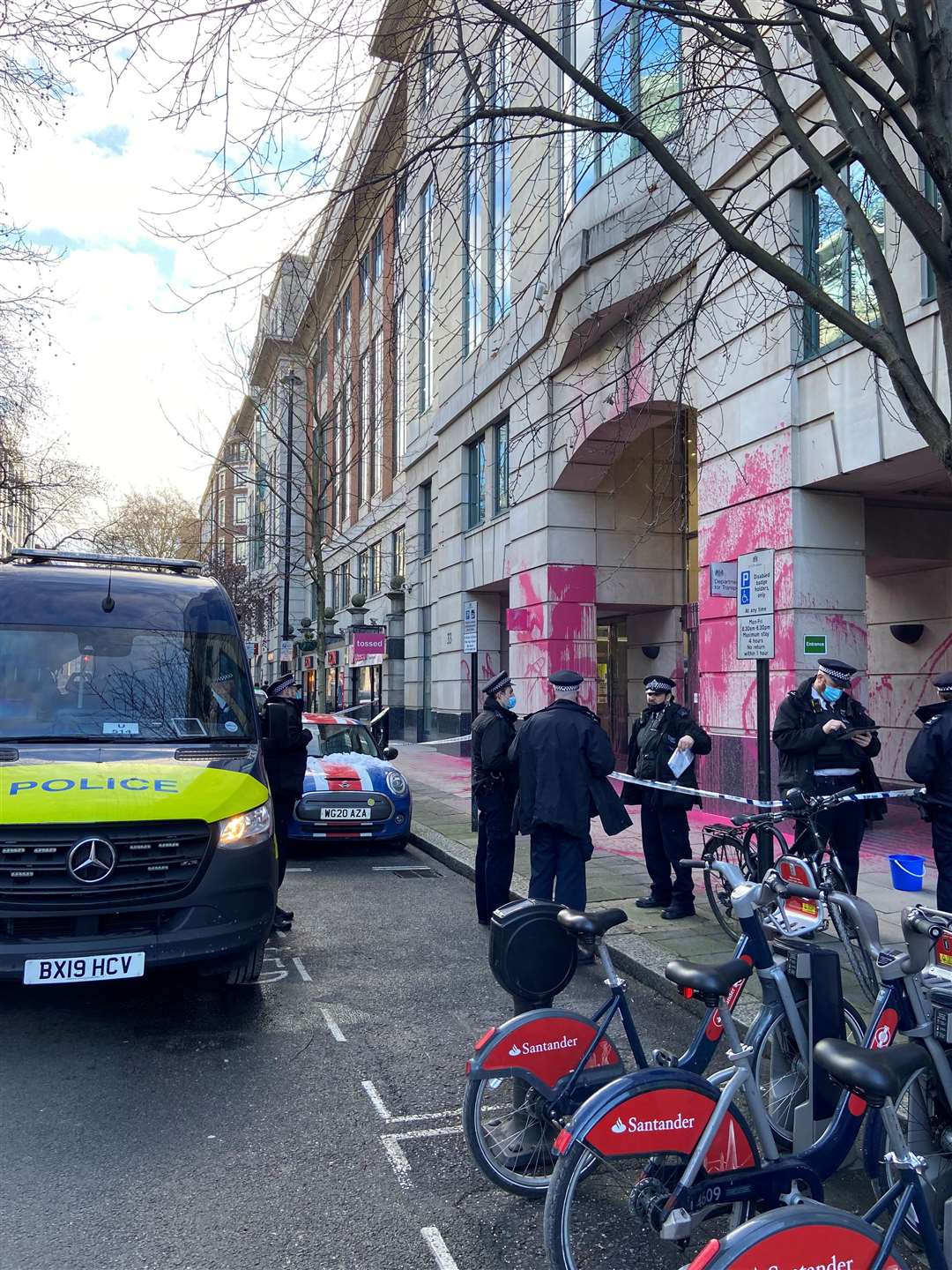 Police outside the Department for Transport, which has been vandalised with pink paint (Lewis McKenzie/PA)