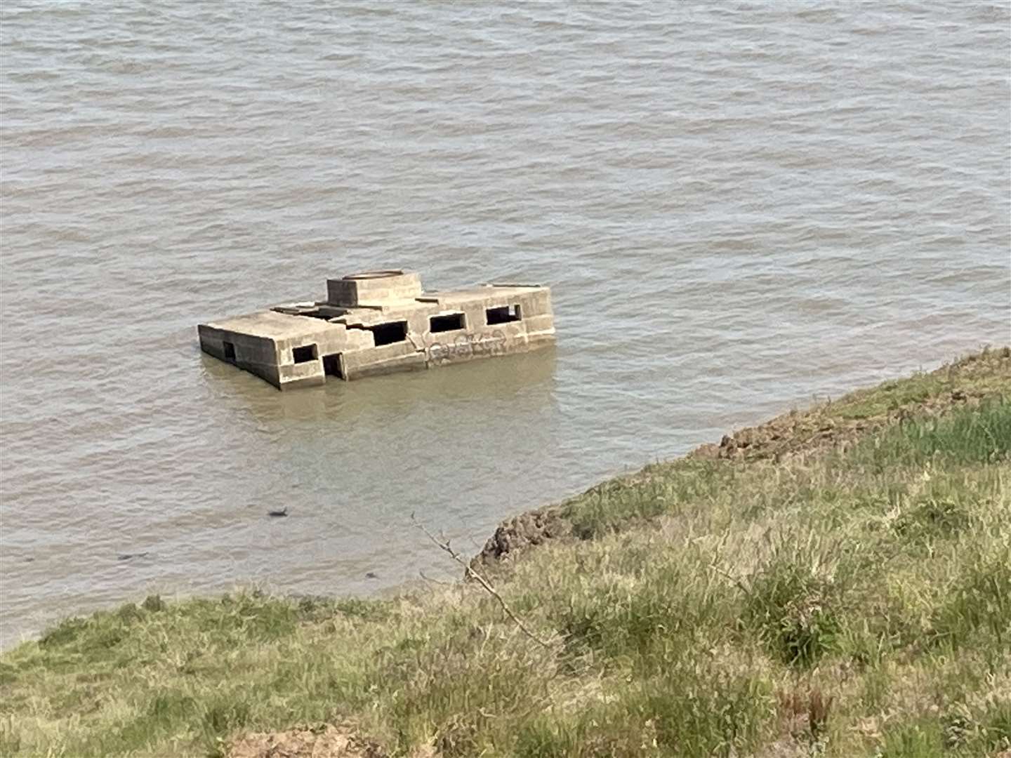 Former Second World War defences surrounded by high tide at Warden cliffs, Sheppey, illustrating the dangers of the coast