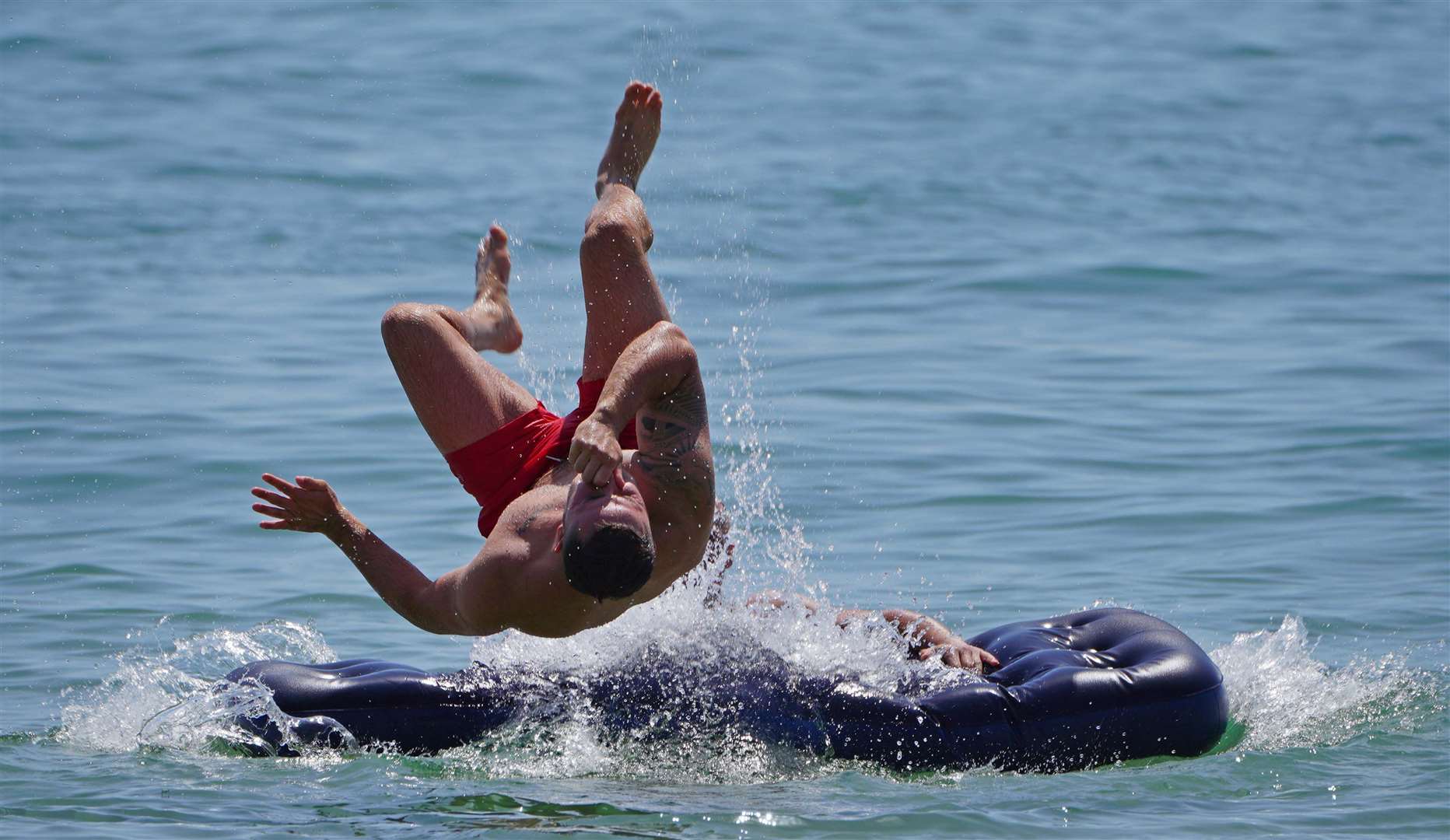 A man jumps off an inflatable lilo off Bournemouth beach in Dorset (Ben Birchall/PA)