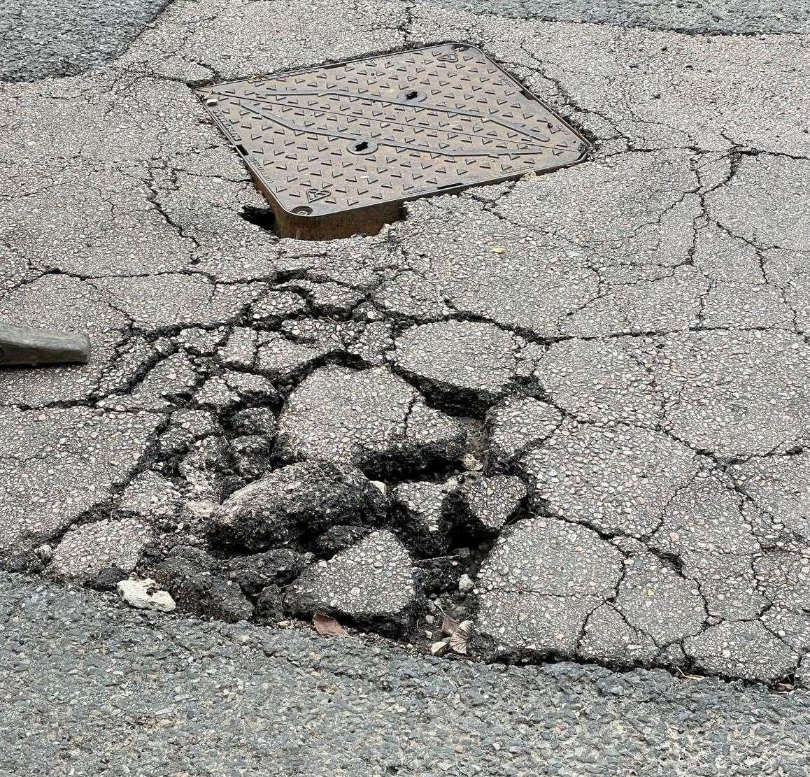 Parts of the tarmac have broken up and the manhole has sunk into the ground