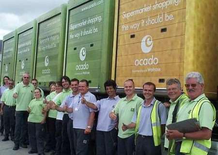 Ocado staff celebrate next to the distinctive and brightly-coloured pods