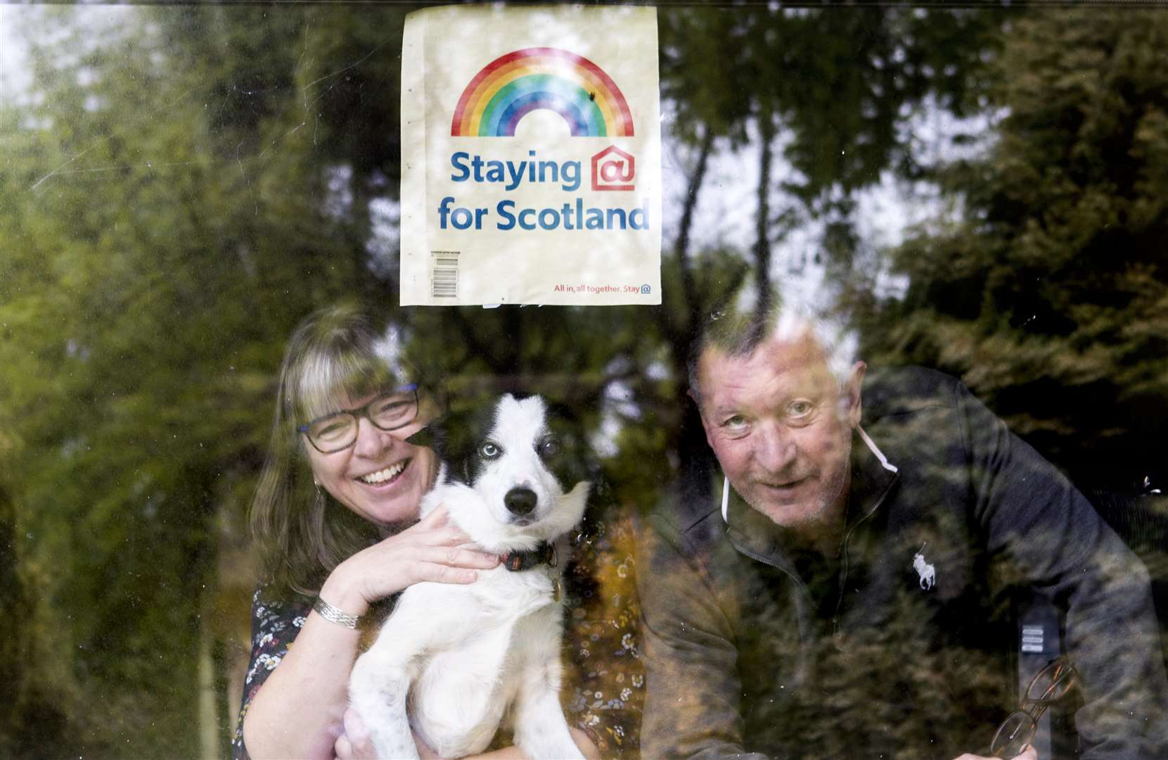 Colin and Margaret Moncur, with their dog Molly, look out from their window in Minard (Jane Barlow/PA)