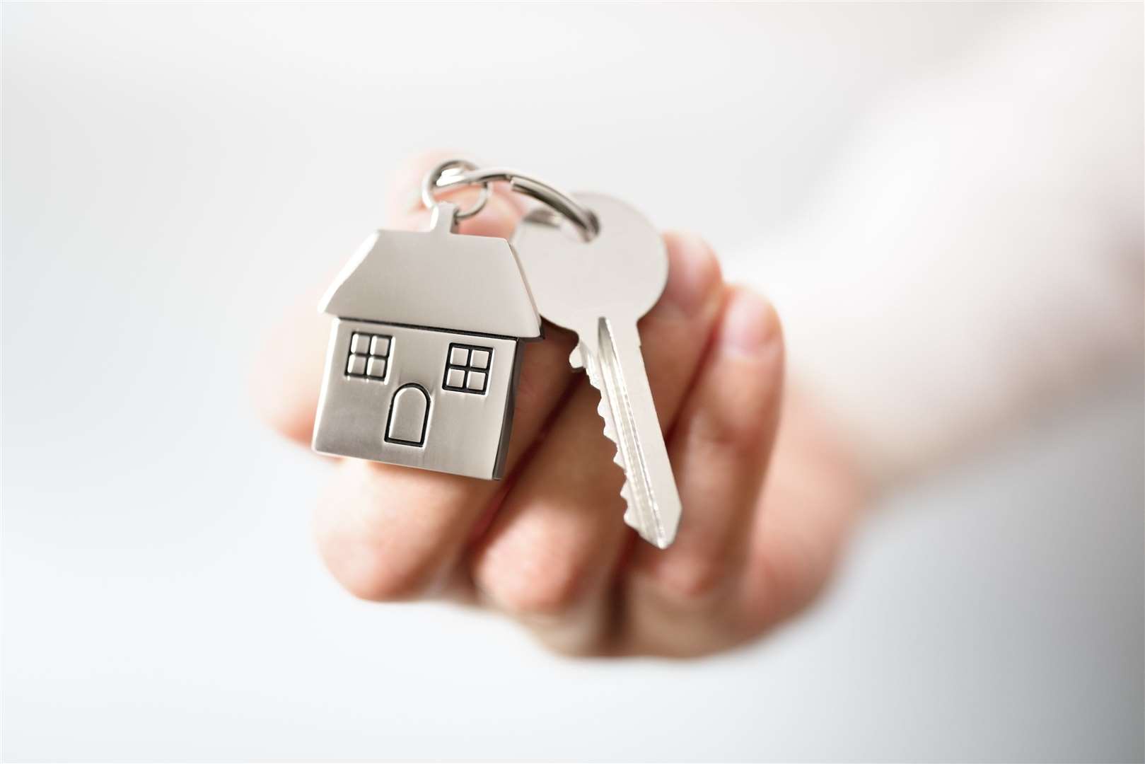 Holding house keys on house shaped keychain concept for buying a new home. (14650566)