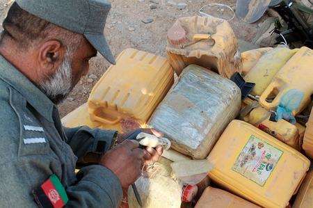 An Afghan policeman examines explosive material discovered in Helmand Province